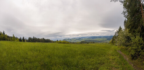 Panorama scenic view of meadow against polish mountains on a way to Lubon wielki famous for hiking trails of varying difficulty located near Rabka in the region of Beskid Wyspowy, Poland
