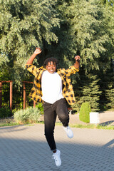 a happy African American woman in the park makes a jump in the summer