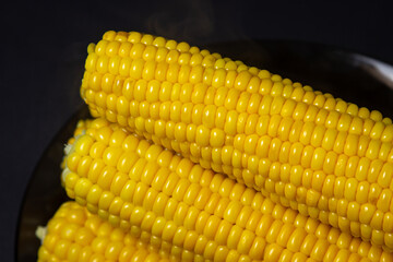 Boiled corn on a black background. Delicious sweet corn. Healthy food