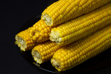 Boiled corn on a black background. Delicious sweet corn. Healthy food