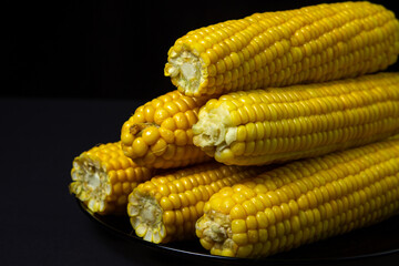 Boiled corn on a black background. Delicious sweet corn. Healthy food