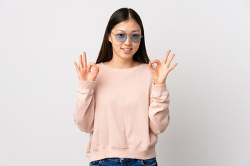 Young Chinese girl over isolated white background showing ok sign with two hands