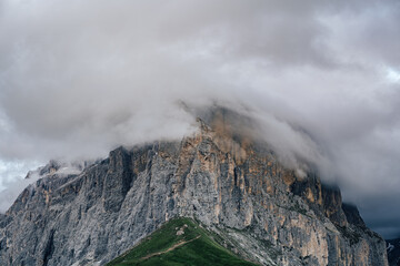 The Sella Group and Sella Towers in the motion blurred clouds. Evening view of high rock walls and towers of Sella group from Sella pass. Clouds and alpine meadows. Dolomites.