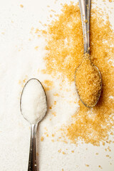 White and brown sugar in tablespoons on the light background with copy space