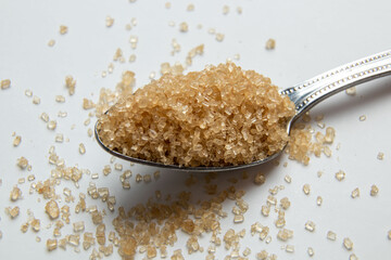 Brown sugar in tablespoons on the light background with copy space, Closeup - obrazy, fototapety, plakaty