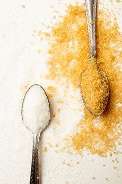 White and brown sugar in tablespoons on the light background with copy space