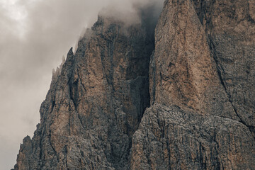 Close up detail photo of rock walls and towers of Dolomites, wrapped in mist and clouds. Steep rock walls in Sella group, Dolomites.