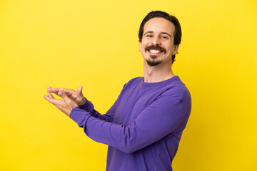 Young caucasian man isolated on yellow background applauding