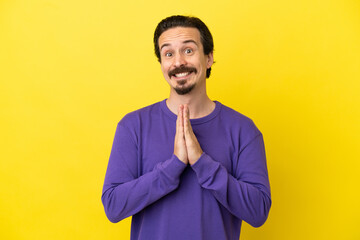 Fototapeta premium Young caucasian man isolated on yellow background keeps palm together. Person asks for something