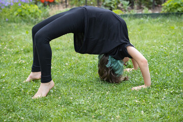 Teenage girl in glasses with multi-colored hair playing on the lawn in a summer garden