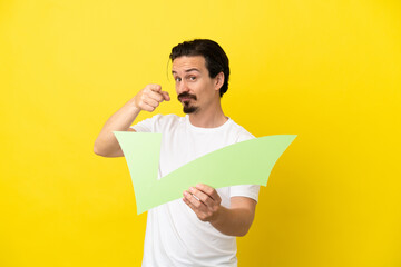 Young caucasian man isolated on yellow background holding a check icon and pointing to the front