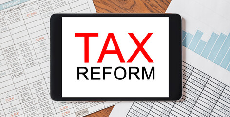 Tablet with text tax reform on your desktop with documents, reports and graphs. Business and...