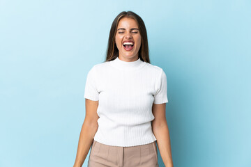 Young Uruguayan woman isolated on blue background shouting to the front with mouth wide open