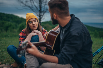 Couple playing guitar and having a romantic date while spending a time in the nature
