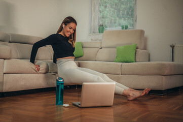Young attractive woman using a laptop while training at home