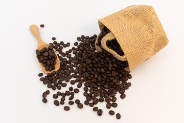 Coffee beans in wooden spoon and hemp sack bag isolated on white background.