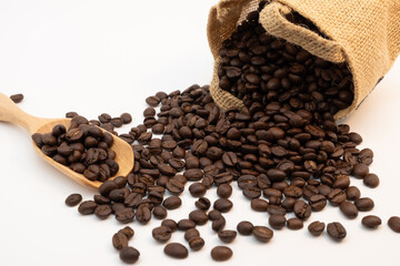 Coffee beans in wooden spoon and hemp sack bag isolated on white background.