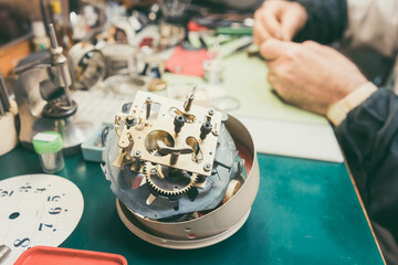 Close up on clockwork of clock to be repaired in watchmaker workshop laying on the workbench
