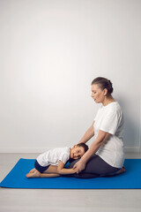 Fototapeta premium grandmother and her grandson are sitting on a yoga mat in a white apartment at home