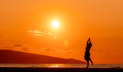 Woman at beach, during sunset, silhouette.