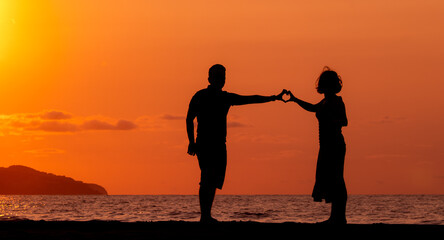 Fototapeta na wymiar Harmony between couple at the beach, silhouette during sunset, lovers.