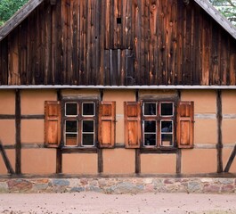 The facade of a wooden country cottage with two windows.