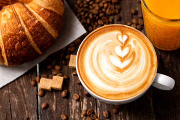 Breakfast is served, croissant, espresso latte and orange juice, wooden table background