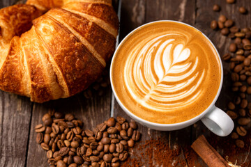 Rustic wooden background with latte coffee and croissant