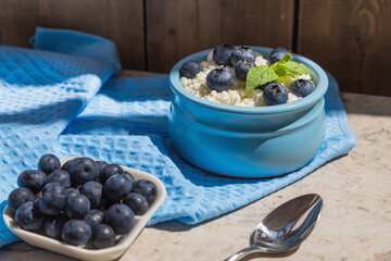 Morning fresh breakfast made from natural products from cottage cheese and blueberries. Nutritious cottage cheese and berries contain healthy vitamins. Blue background.