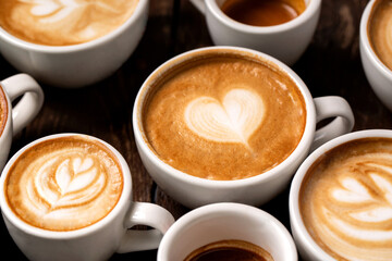 White coffee cups with heart shaped and rosette latte art on a wooden table