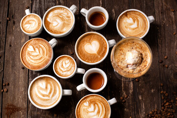 Dozen coffee cups with beverages in them, latte art, macchiato, espresso, wooden background