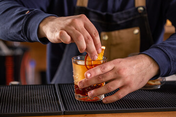Close up of bartender hands decorating a cocktail glass with a orange slice