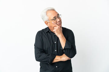 Middle age Brazilian man isolated on white background thinking an idea while looking up