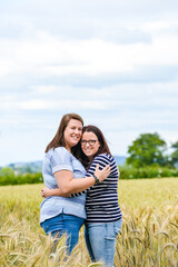 Happy lesbian couple in the field smiling at the camera 
