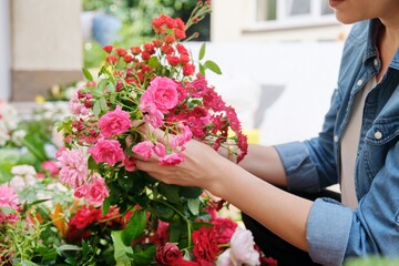 Female florist working with flowers outdoors, decorating events with flowers