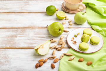 Green macarons or macaroons cakes with cup of coffee on a white wooden background. Side view, copy space.