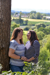Lesbian couple smiling at each other with a beautiful background. 