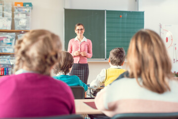 Teacher in school class with pupils sitting and listening attentively
