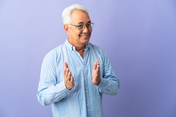 Middle age Brazilian man isolated on purple background applauding after presentation in a conference