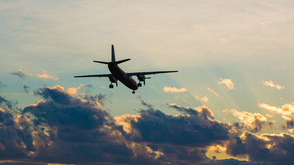 The plane is landing against the backdrop of a dramatic sky at sunset. airlines, flight, travel, tourism, trip.