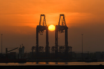 Gantry crane with sunrise sun. Morning at port.