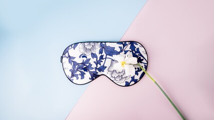 Beautiful silk sleep mask for eyes with flowers pattern and white narcissus or daffodil flower on a...