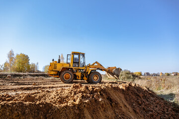 large yellow wheel loader aligns a piece of land for a new building. Preparation of the land for the auction. Leveling the landscape and adding sand for construction. Banner wallpaper