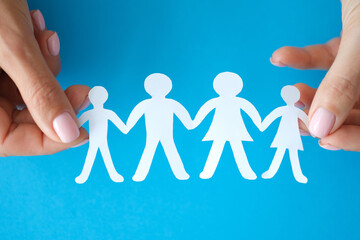 Female hands showing family of paper figures closeup