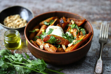 Baked carrots in a bowl with cream cheese, cilantro and nuts.