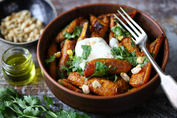 Baked carrots in a bowl with cream cheese, cilantro and nuts.