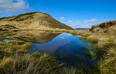 Small picturesque lake with clouds reflections at the  Strymba Mount. Beautiful autumn day in Carpathian Mountains near Kolochava village, Transcarpathia, Ukraine.