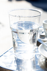 Transparent plastic glass with non alcoholic liquid on metal table in outdoor bar. Drinking water problem concept. Healthy dieting. 