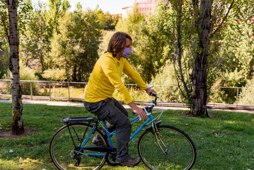 Man wearing face mask in the park riding bike