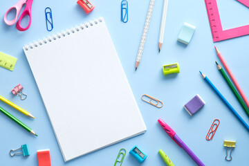 School stationery and notepad on blue background. Back to school concept. Flat lay, top view, overhead